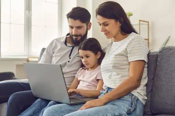 Parents and little girl on laptop video chatting with therapist