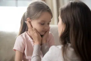 Mother holding her 6 year old daughter's face in her hands.