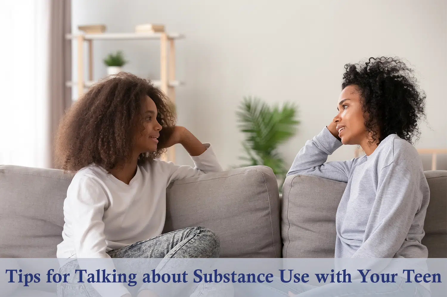 Mother and daughter sitting on a grey couch talking about substance use.