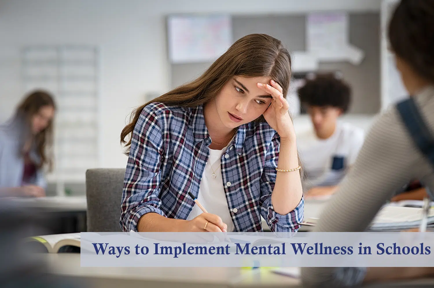 White female student with long brown hair and blue flannel anxiously sitting in classroom, needing mental wellness support.